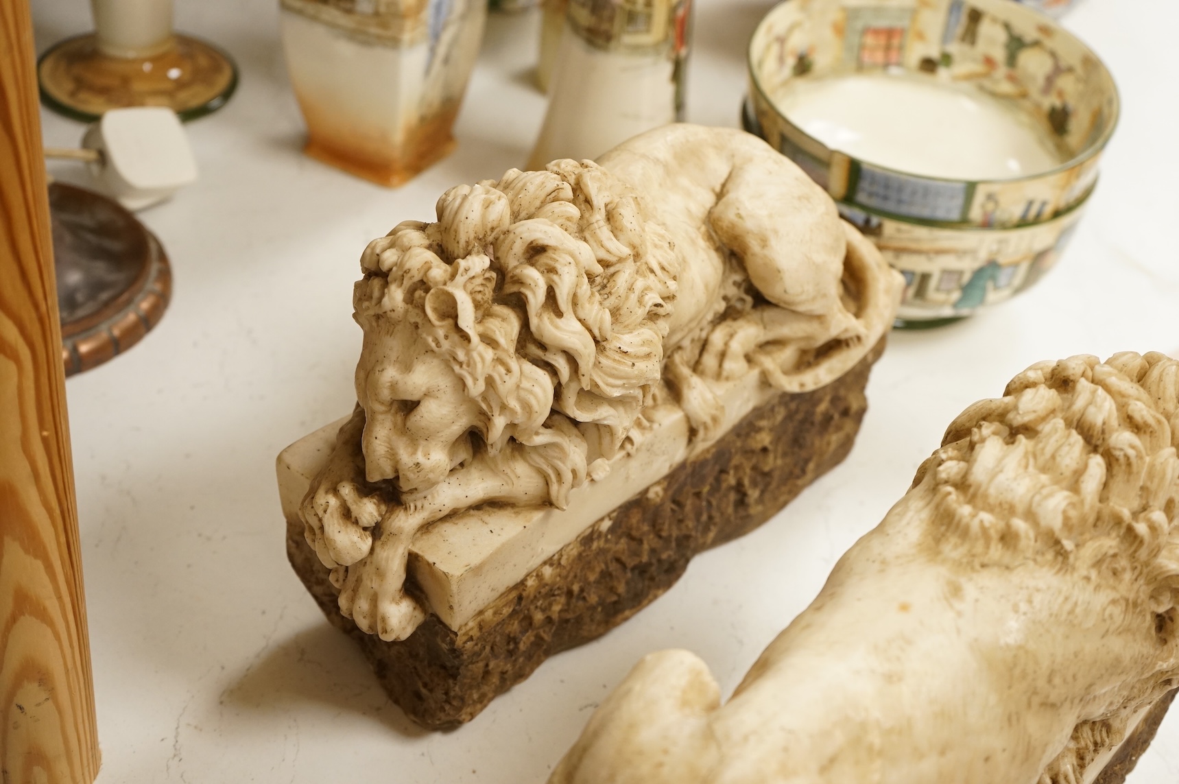 A pair of 20th century faux marble models of recumbent lions, 31cm